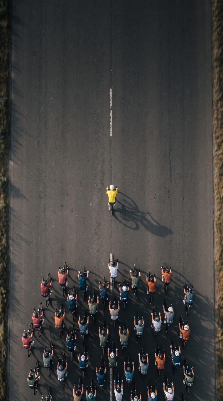 Lone cyclist in a yellow jersey riding clear of the peloton